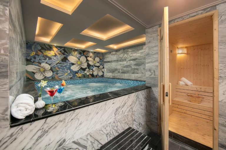 Jacuzzi de mármol con mosaico floral y sauna de madera en el spa del Anatole Hotel Hanoi