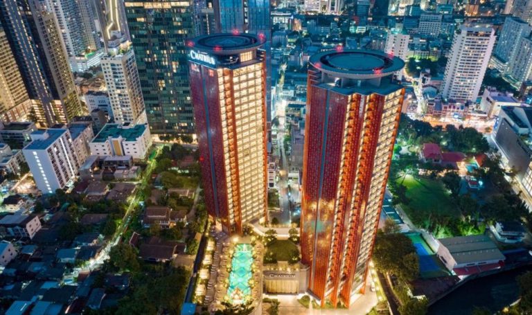 Vista aérea nocturna de las torres del Chatrium Grand Bangkok con piscina exterior iluminada