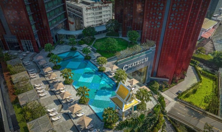 Vista aérea de la piscina exterior con tumbonas y jardines tropicales del Chatrium Grand Bangkok