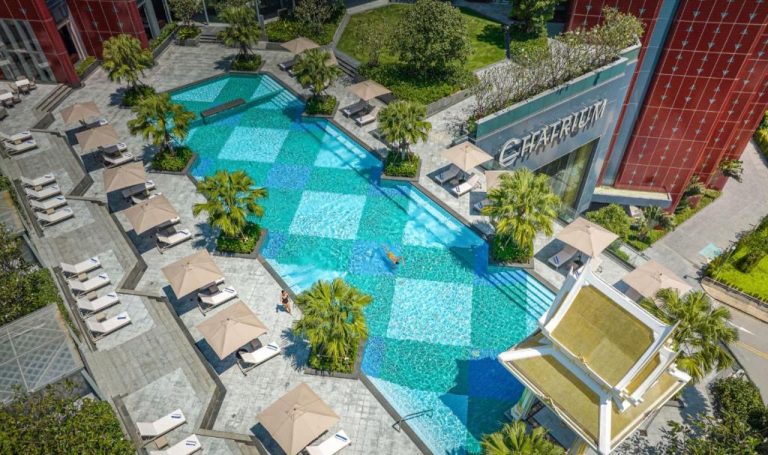 Vista aérea de la piscina exterior con tumbonas y palmeras del Chatrium Grand Bangkok