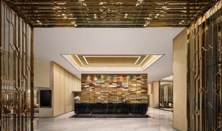 Lujoso lobby con recepción de mármol y decoración dorada del Chatrium Grand Bangkok