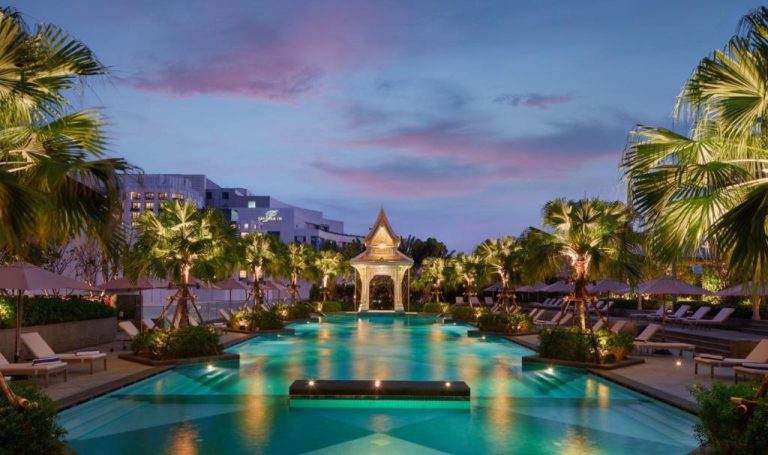 Piscina exterior iluminada con pabellón tailandés del Chatrium Grand Bangkok al atardecer