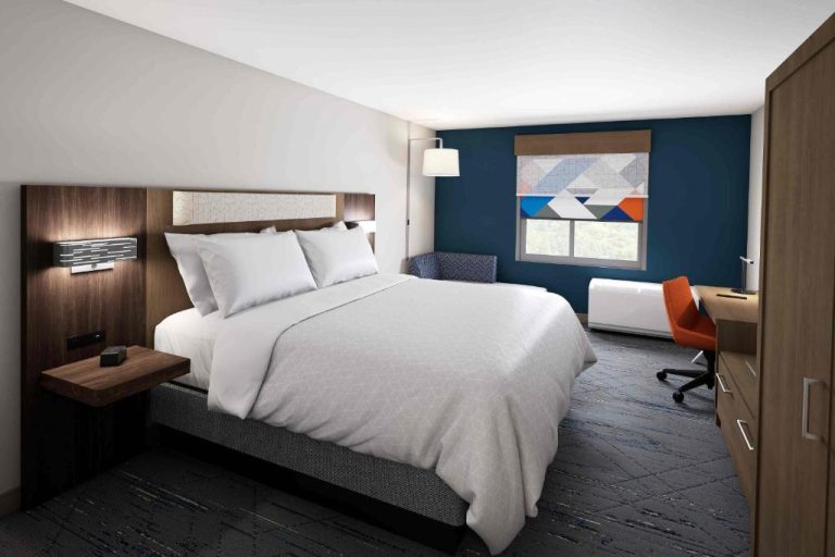 Habitación king con escritorio y pared azul en Holiday Inn Express Starke by IHG