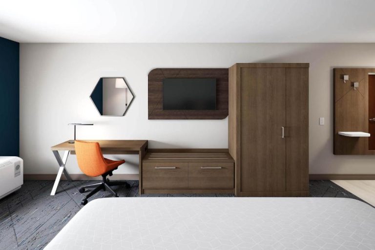Habitación moderna con escritorio, silla naranja, televisor y armario en Holiday Inn Express Starke