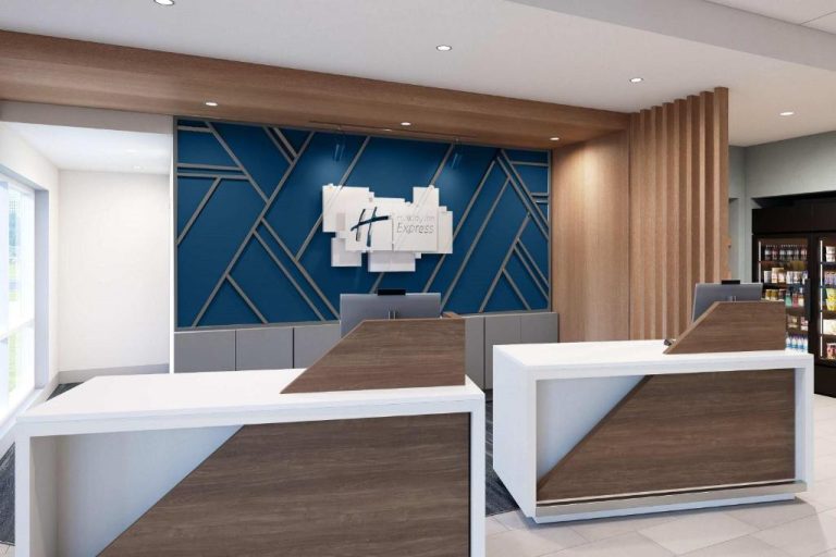 Recepción moderna del Holiday Inn Express Starke con mostrador de madera y pared decorativa azul