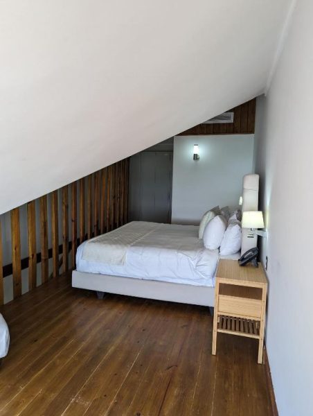 Habitación abuhardillada con cama doble y suelo de madera en Hacienda Samana Bay Hotel