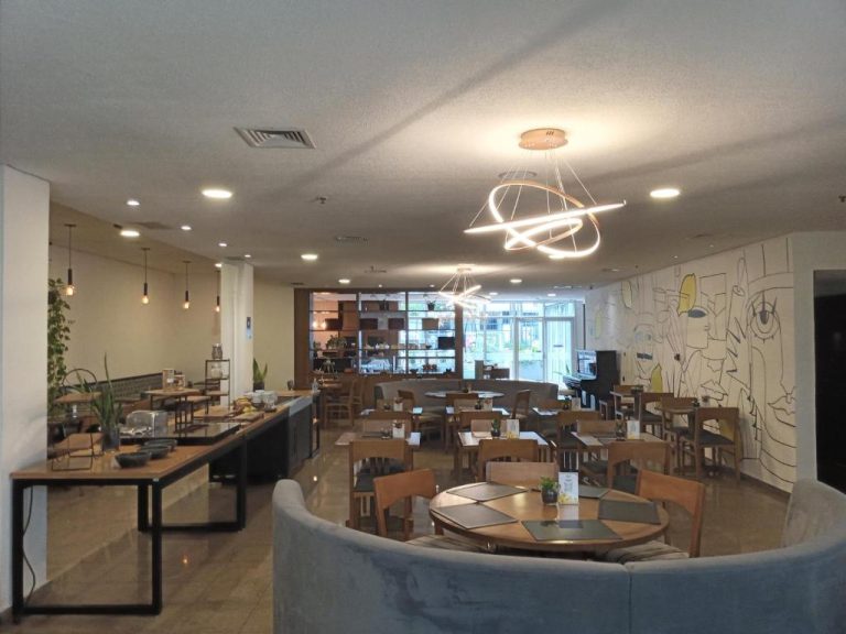 Restaurante moderno con mesas de madera y mural artístico en hotel 4 estrellas Avenida Paulista São Paulo