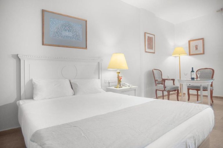 Habitación doble con cama king size y decoración blanca elegante en Grand Hotel Madaba, Jordania