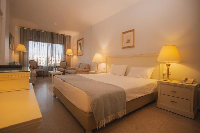 Habitación doble clásica con cama king size y zona de estar en el Grand Hotel Madaba, Jordania