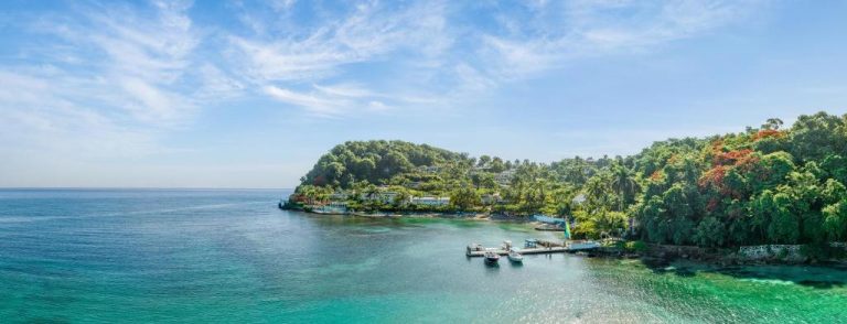 Vista aérea de la bahía tropical del Round Hill Hotel & Villas con muelle privado y vegetación exuberante