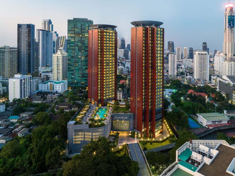 Vista aérea del Chatrium Grand Bangkok con sus dos torres rojizas, piscina exterior y skyline de Bangkok al atardecer