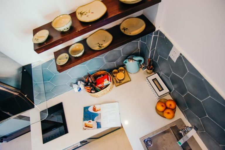 Cocina equipada con estantería de madera, vajilla cerámica y encimera blanca en Phuong Tran Apartment and Hotel