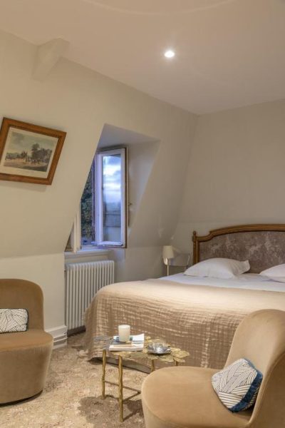 Habitación doble clásica con cama de madera y sillones del Château de Saulon en Borgoña
