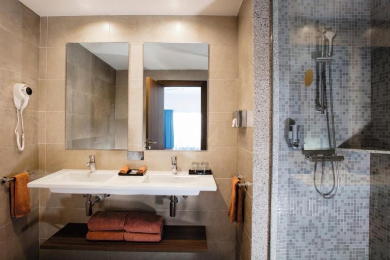 Baño moderno con doble lavabo y ducha de azulejo en el hotel Riu Santa Fe All Inclusive