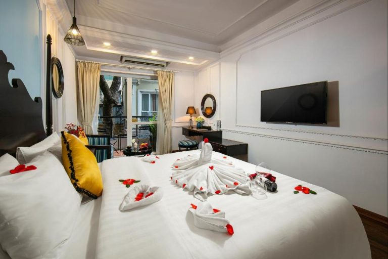 Habitación romántica con pétalos de rosa y toallas decoradas en San Boutique Hotel & Travel