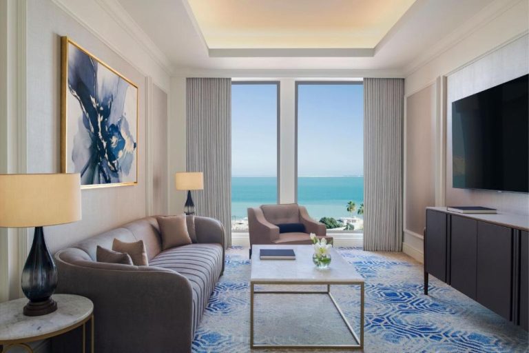Salón de suite de lujo con vistas al mar turquesa en The St. Regis Doha, Qatar