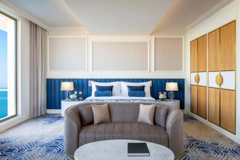 Suite de lujo con cama king y cabecero azul con vistas al mar en The St. Regis Doha