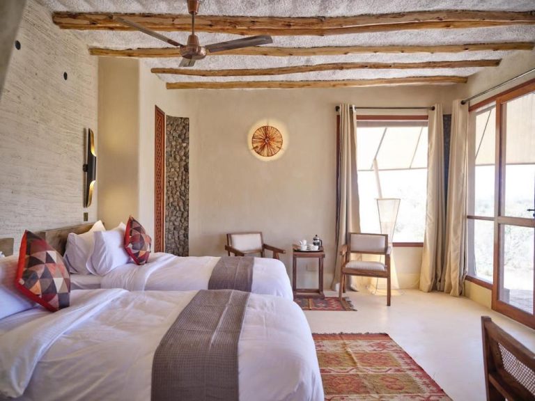 Habitación doble con vigas de madera y decoración rústica africana en Surana Buffalo Springs