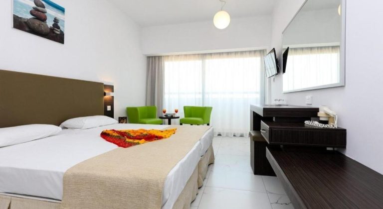 Habitación doble estándar con cama grande y sillones verdes en el Christofinia Hotel