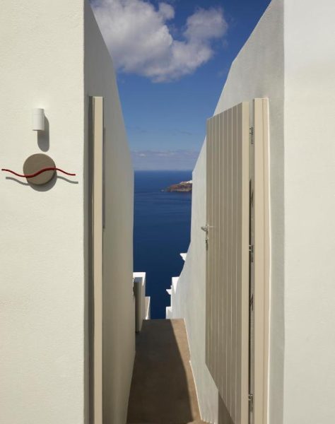 Entrada con puerta blanca y vistas al mar azul del Mediterráneo en Atoles Retreat Santorini