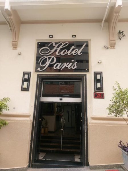 Entrada principal y fachada del Hotel Paris con letrero iluminado y puerta automática de acceso