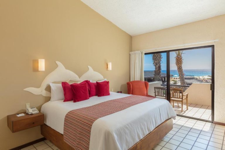 Habitación king size con cabecero de delfines y terraza con vista al mar en Solmar Resort