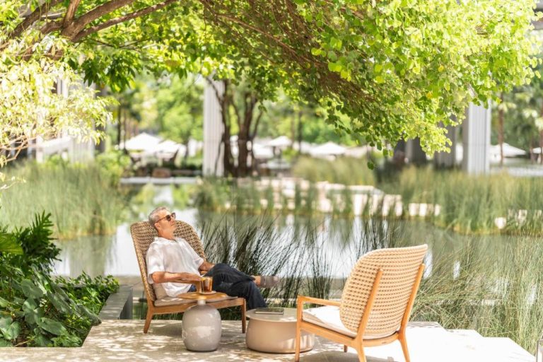 Huésped relajándose en jardín junto al lago del Four Seasons Hotel Bangkok at Chao Phraya River