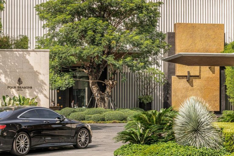 Entrada principal del Four Seasons Hotel Bangkok con jardines tropicales y coche de lujo