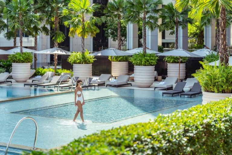 Piscina exterior con tumbonas y palmeras del Four Seasons Hotel Bangkok at Chao Phraya River