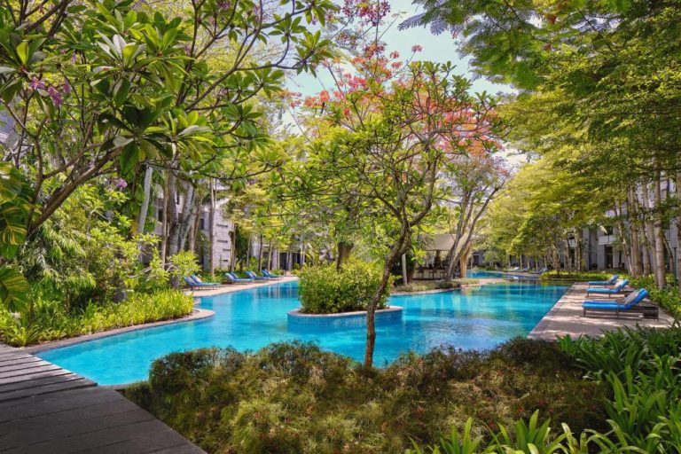 Piscina exterior rodeada de jardín tropical con tumbonas en Courtyard by Marriott Bali Nusa Dua Resort