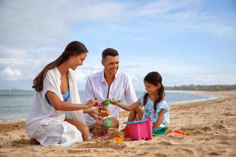 Familia jugando en la playa con castillos de arena en el Courtyard by Marriott Bali Nusa Dua Resort