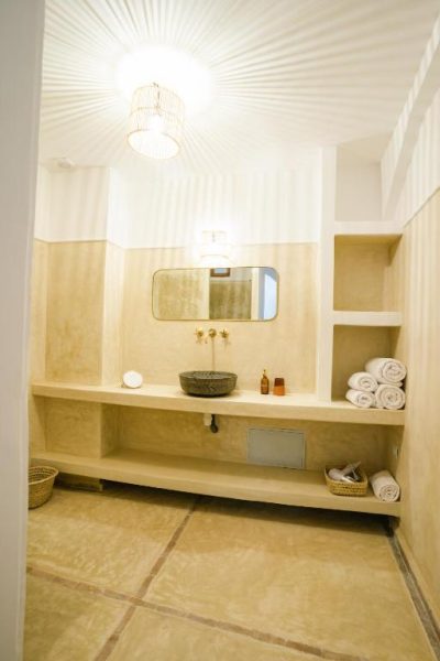 Baño de estilo marroquí con lavabo de piedra y estantes empotrados en el Riad Rahal