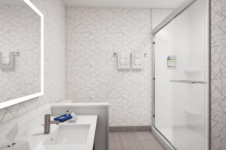Baño moderno con ducha de cristal y lavabo blanco en Holiday Inn Express Starke by IHG
