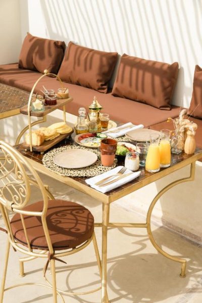 Desayuno marroquí servido en terraza exterior del Riad Rahal con zumos frescos y pan
