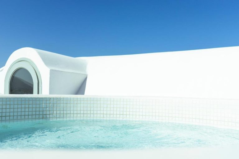 Jacuzzi exterior con vistas al cielo azul y arquitectura blanca del Astro Palace Hotel & Suites en Santorini