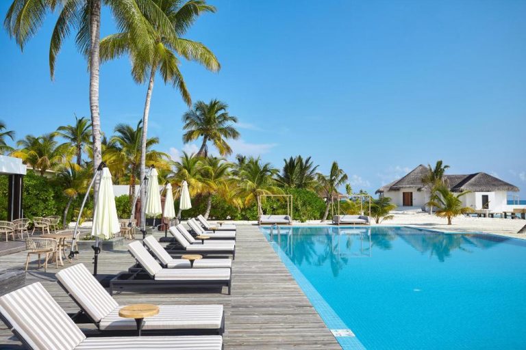 Piscina infinita con tumbonas y palmeras tropicales frente a la playa en NOOE Maldives Kunaavashi