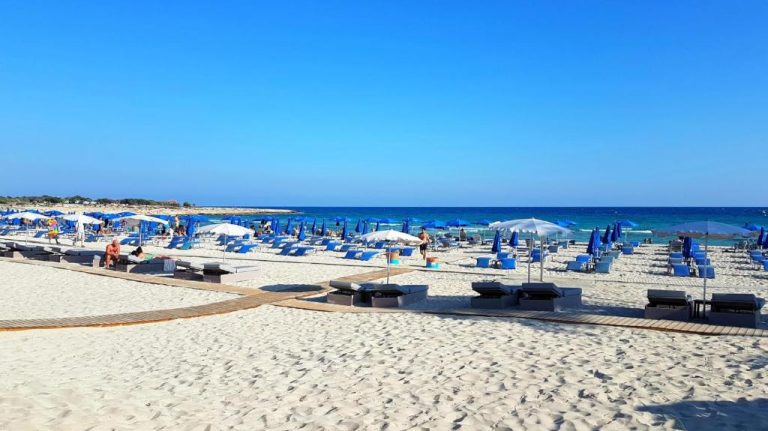 Playa de arena blanca con tumbonas y sombrillas azules del Tsokkos Paradise Holiday Village