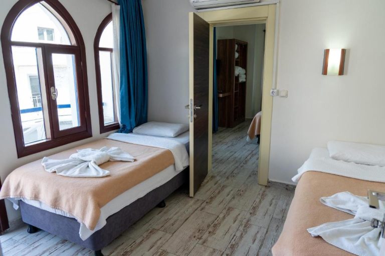 Habitación triple con tres camas individuales y ventanas de arco en Eroglu City Hotel