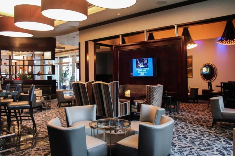 Elegante lobby lounge con bar, sillones modernos y televisión en suite de lujo en Las Vegas