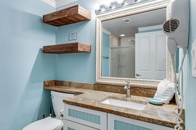 Baño moderno con encimera de granito, espejo ornamental y estantes de madera en Shores of Panama 2030