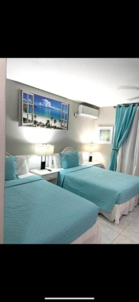 Habitación doble con camas azules y decoración tropical en Ocho Rios Vacation Resort Property Rentals