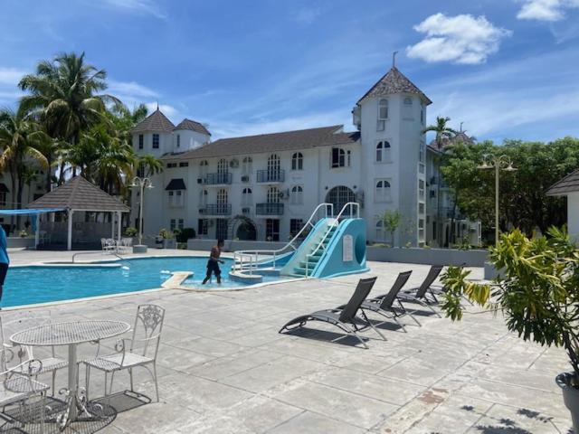 Piscina exterior con tobogán azul y tumbonas del Ocho Rios Vacation Resort en Jamaica