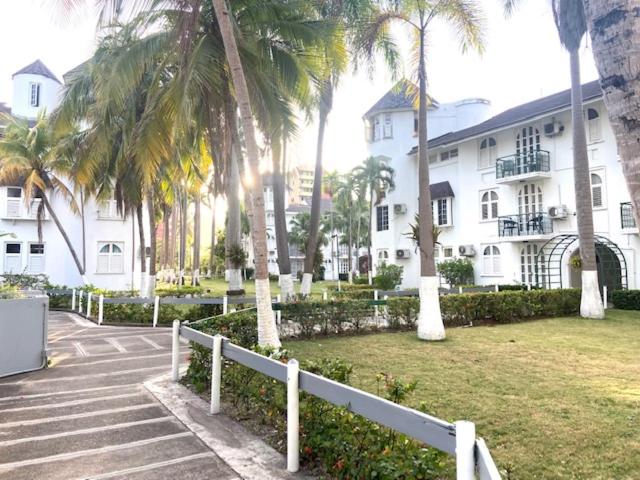 Jardines tropicales con palmeras y edificio blanco colonial del Ocho Rios Vacation Resort en Jamaica
