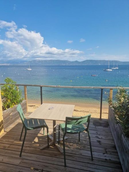 Terraza con mesa y sillas frente a la playa y el mar azul del Hotel L'Escale