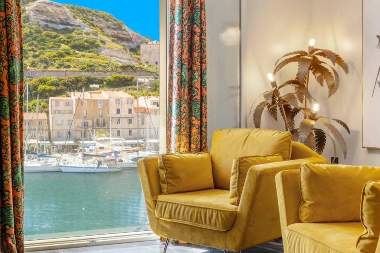 Salón con sillones amarillos y vistas al puerto deportivo y acantilados en Hotel Solemare