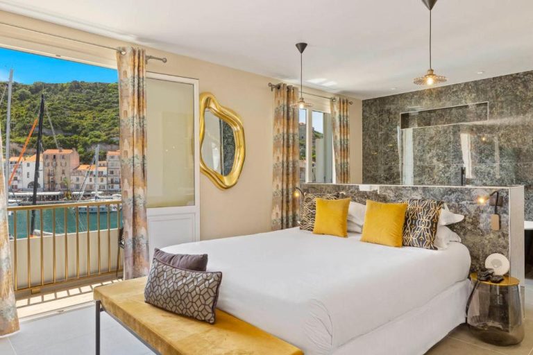 Habitación doble de lujo con vistas al puerto y decoración en dorado del Hotel Solemare