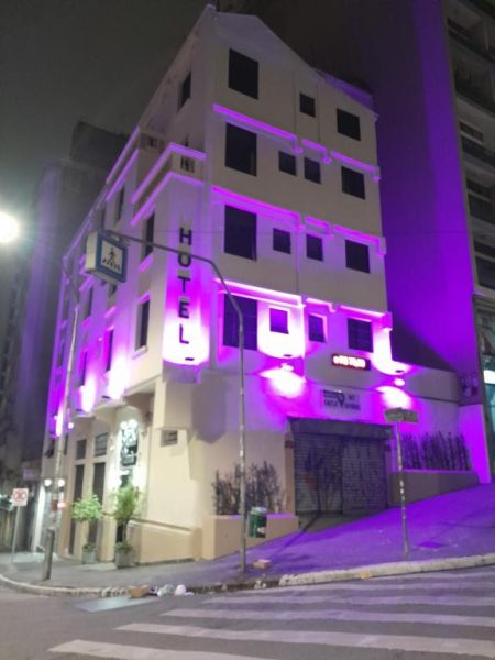 Fachada del Hotel Paris iluminada con luces moradas y violetas durante la noche en esquina urbana