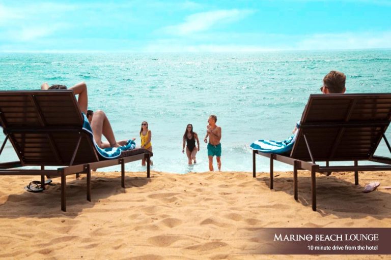 Tumbonas frente al mar en la playa privada del Marino Beach Colombo con bañistas disfrutando del océano