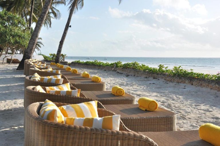 Tumbonas de mimbre con cojines amarillos frente a la playa en Ocean Village Club Adults Only
