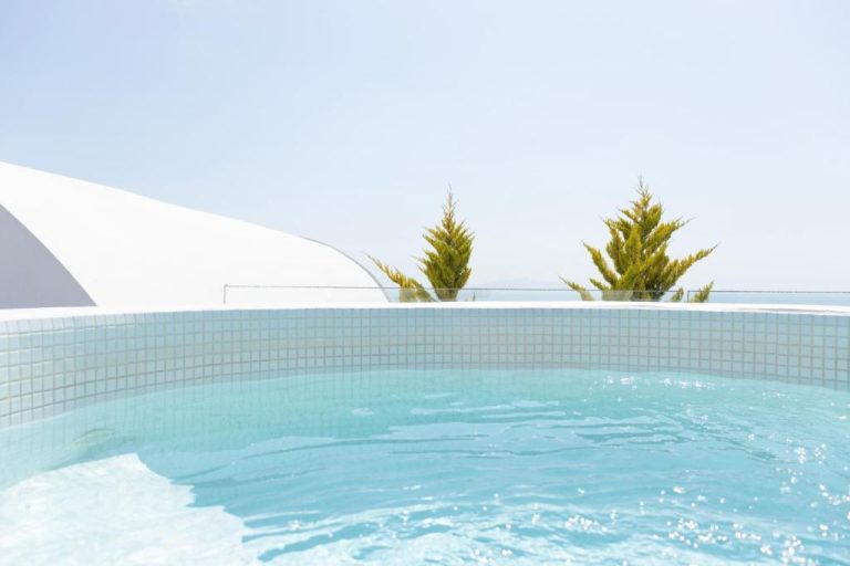 Jacuzzi exterior con vistas al mar y vegetación mediterránea en Astro Palace Hotel & Suites